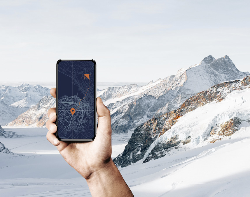 Une main tient un smartphone affichant une carte de navigation avec un itinéraire, face aux Alpes enneigées, la stratégie numérique confrontée au terrain réel